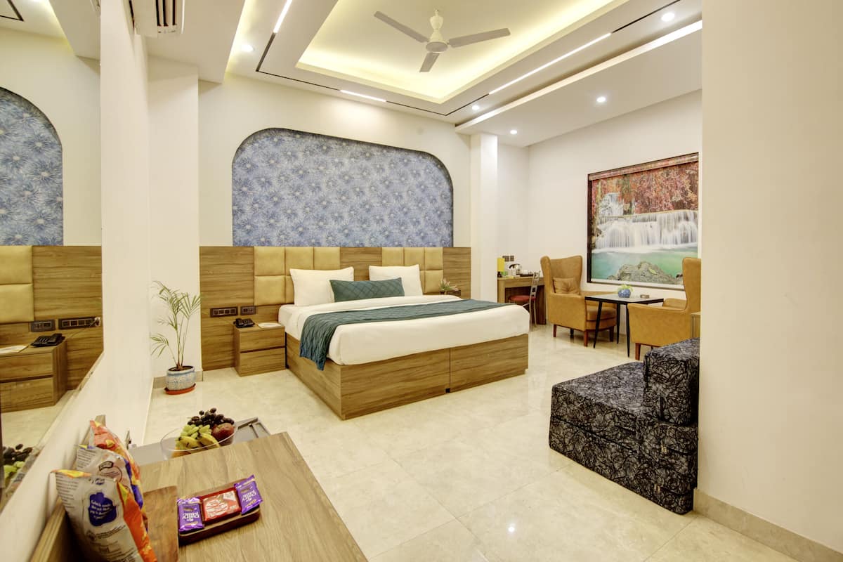 A modern hotel room with a large bed, a desk, and a seating area.