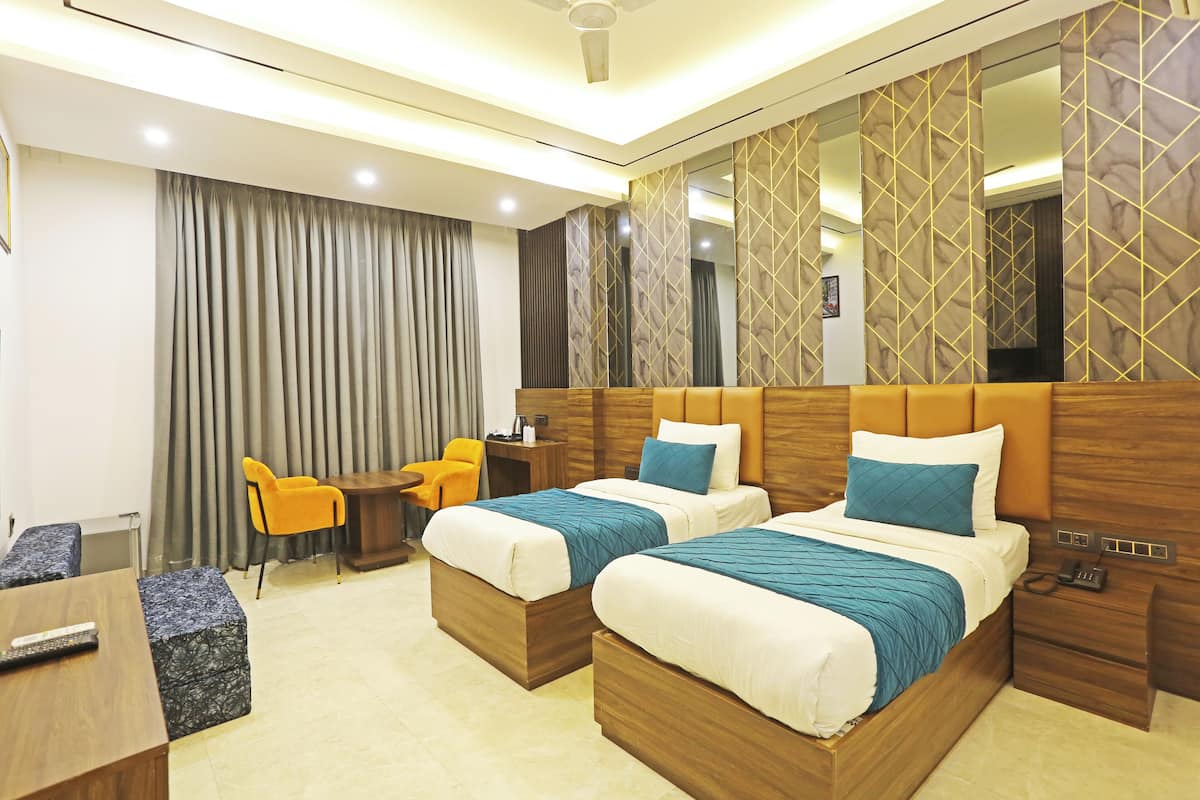 A hotel room with two beds, a desk, a chair, and a large mirror.
