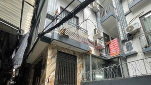 A narrow alleyway with a gated entrance, a parked scooter, and a building with multiple balconies and air conditioning units. - HB Apartment Kim Ma (Hanoi)