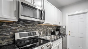 A modern kitchen with a stainless steel stove, microwave, and sink. - Furnished 1BR Near Downtown & UH – Monthly OK (Houston)