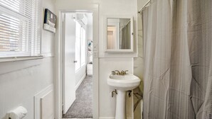 A bathroom with a white sink, a mirror, and a shower curtain. - Furnished 1BR Near Downtown & UH – Monthly OK (Houston)
