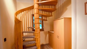 A wooden spiral staircase in a hallway with a wooden cabinet and a window. - Vacation home with garden Carinthia (Kötschach - Mauthen)