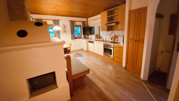 A modern kitchen with wooden cabinets, a dining area with a table and chairs, and a built-in oven. - Vacation home with garden Carinthia (Kötschach - Mauthen)