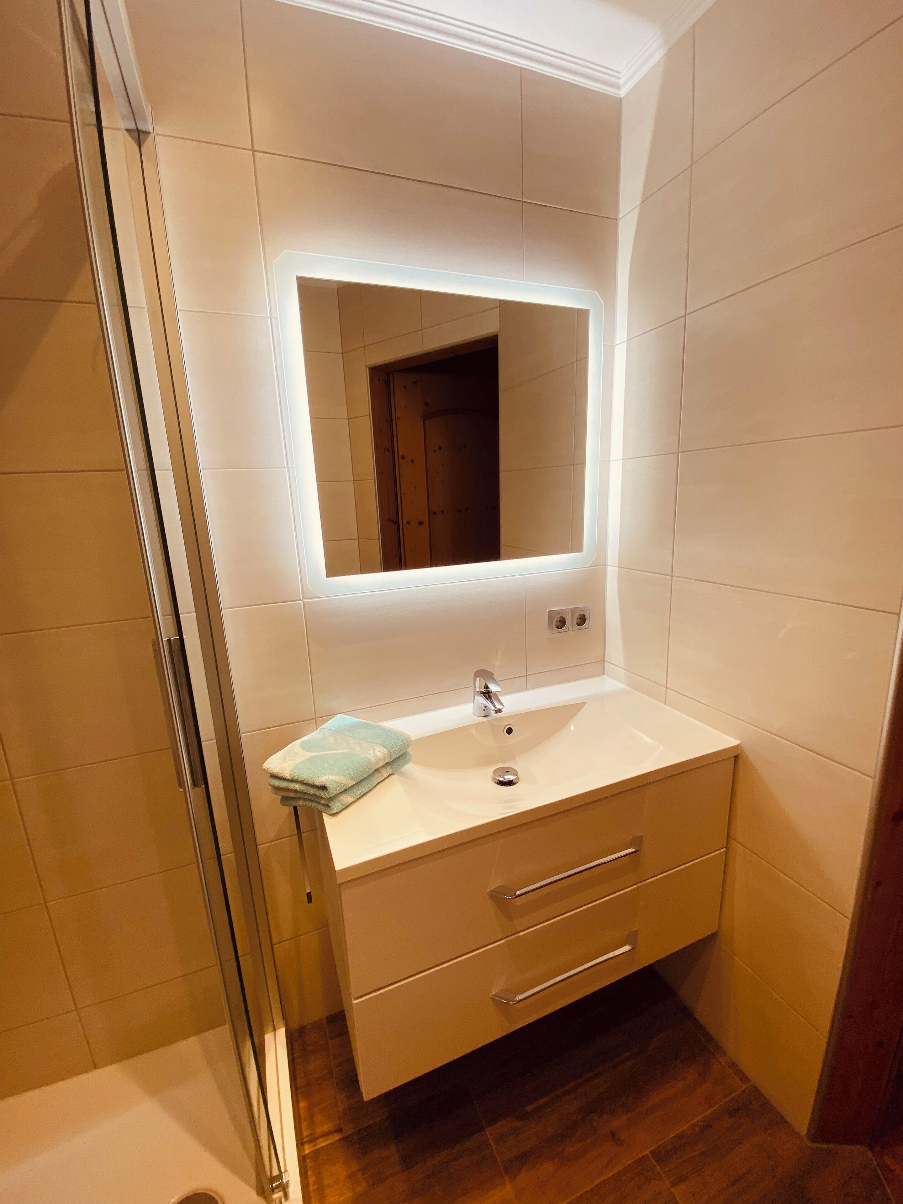 A bathroom with a white sink, a mirror, and a towel.