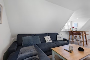 Ein modernes Wohnzimmer mit einem dunkelgrauen Sofa, einem Holztisch und einem Essbereich mit einem Holztisch und Stühlen.