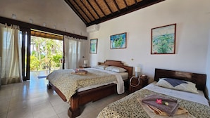 Une chambre d’hôtel avec deux lits, une grande fenêtre avec des rideaux et une vue sur la verdure.