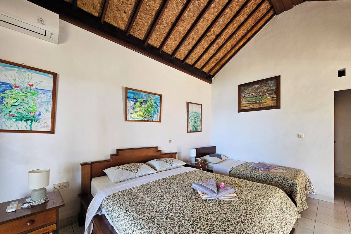 Ein Schlafzimmer mit zwei Betten, einem hölzernen Kopfteil, einem Nachttisch und einem Bild an der Wand.