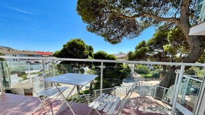 Un balcón con mesa y sillas, con vistas a un jardín y edificios.