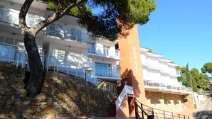 Un edificio moderno con balcones, una pared de piedra y una escalera que lleva a la entrada.