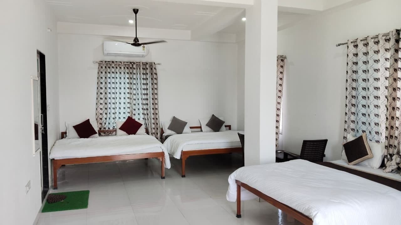 A hotel room with two beds, a ceiling fan, an air conditioning unit, and patterned curtains.