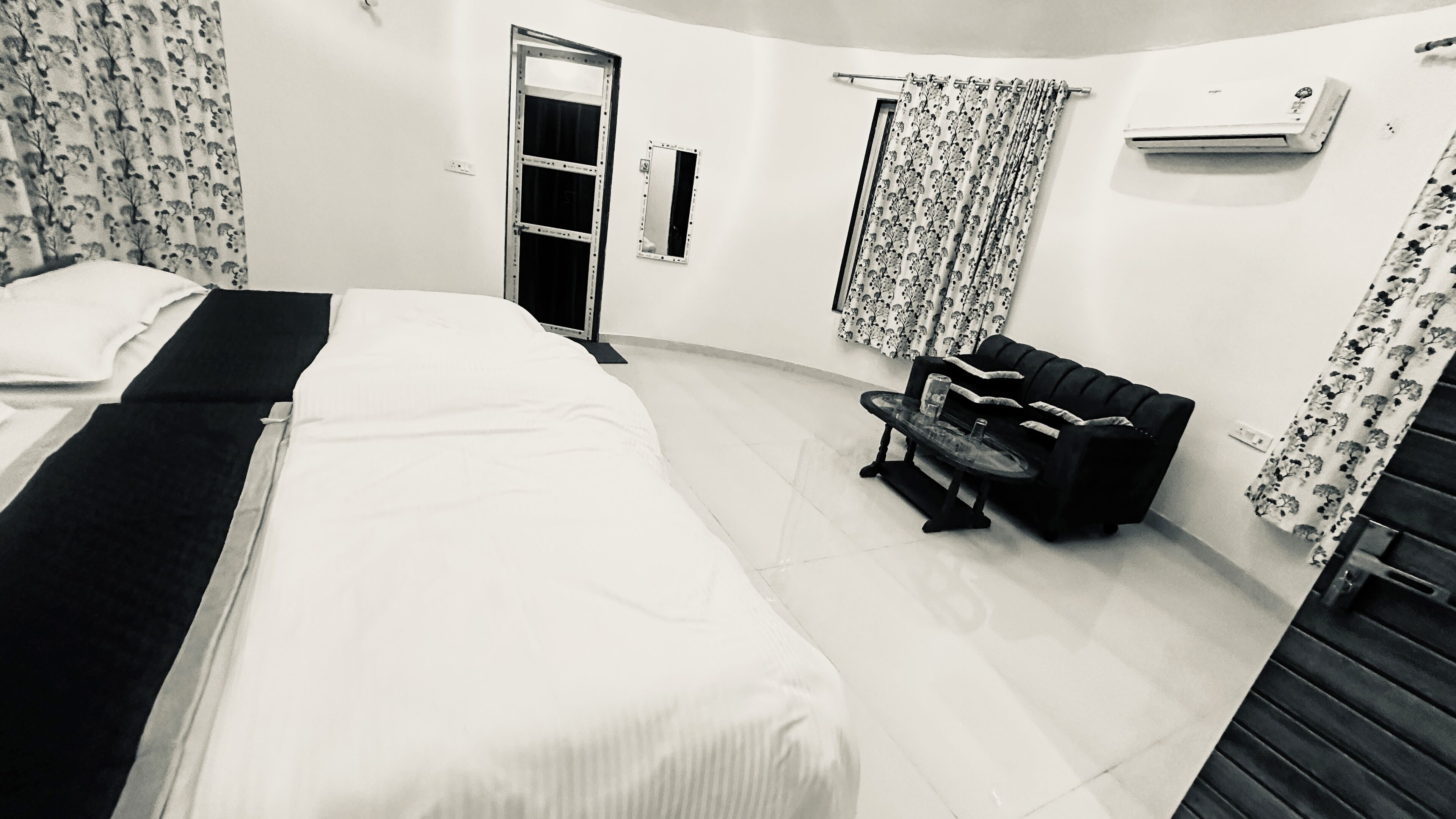 Een hotelkamer met een bed, een tafeltje, een bank en een raam met gordijnen.