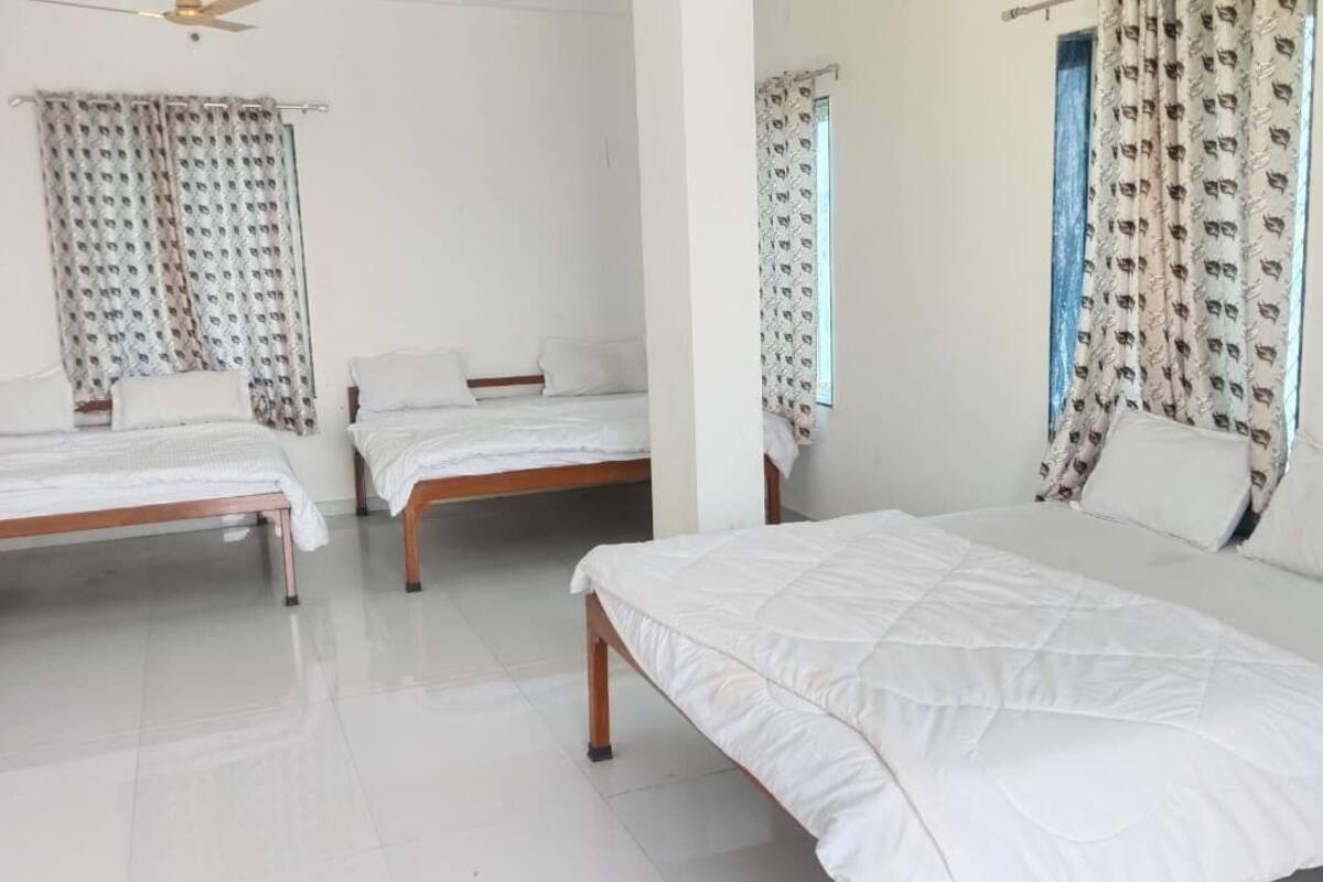 Habitación de hotel con tres camas individuales, una cama grande y un ventilador de techo.