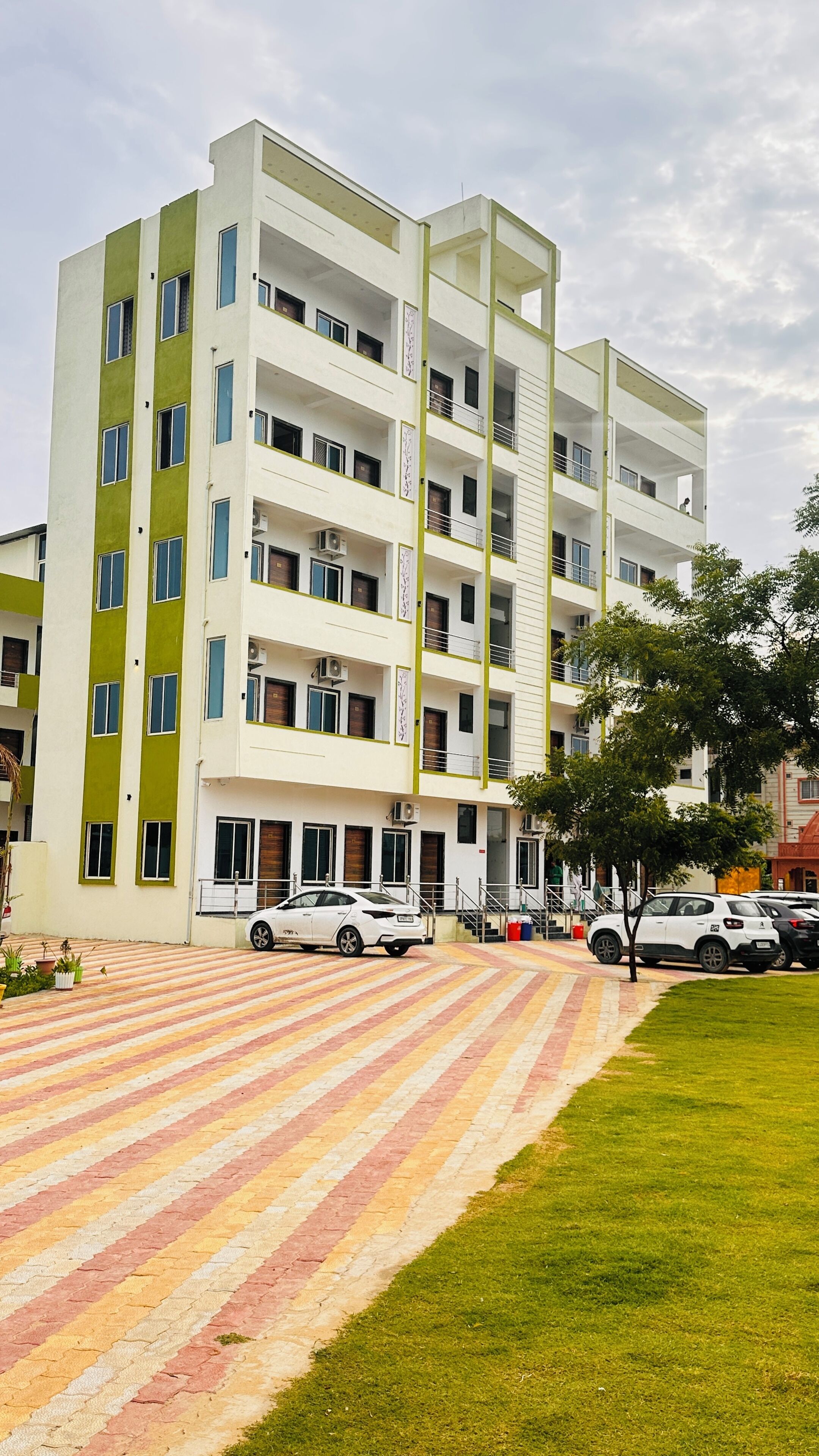 Un edifici residencial de diverses plantes amb teulada plana i una zona de pàrquing al davant.