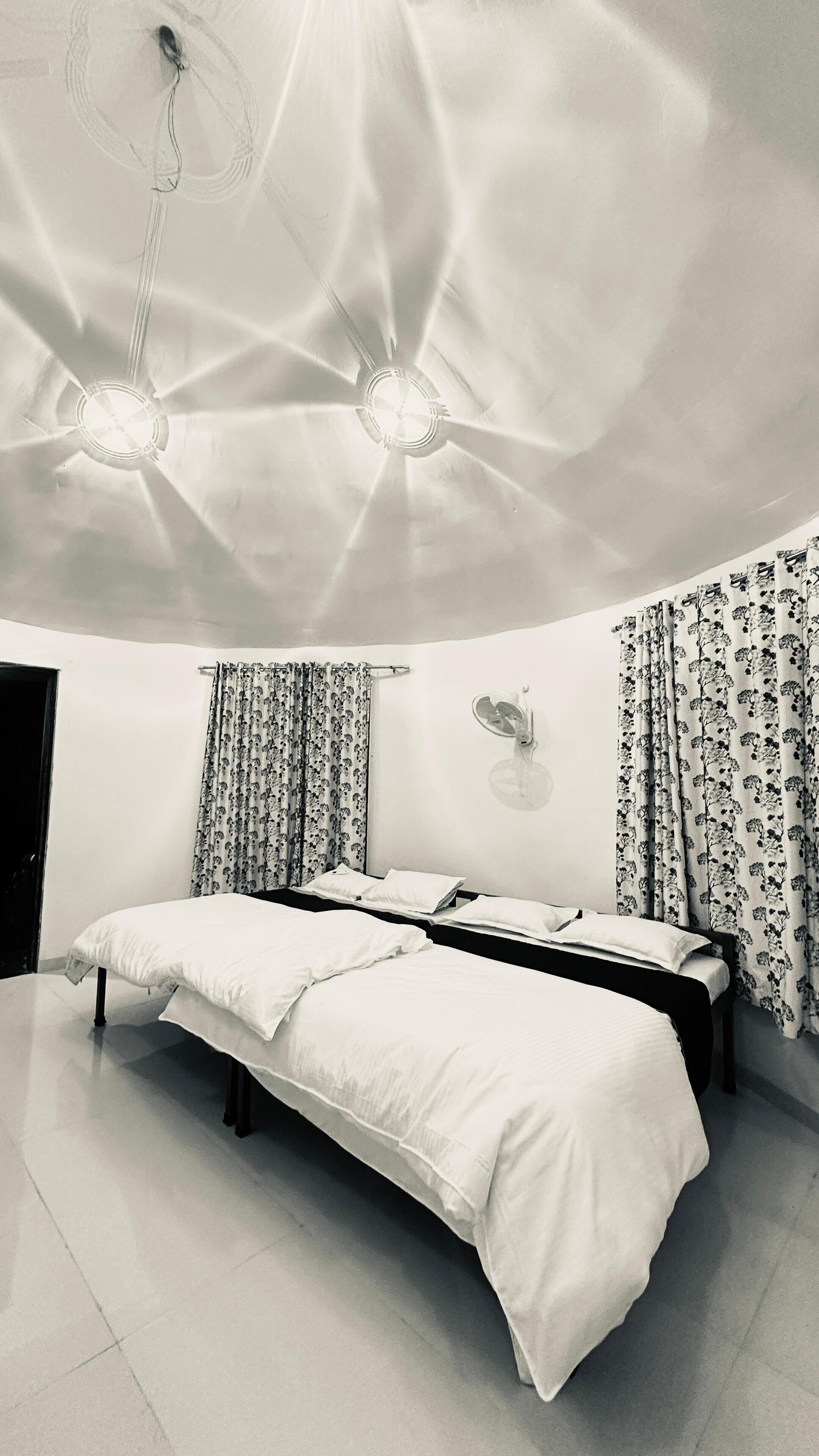 Un dormitorio con una cama grande, dos mesitas de noche, una lámpara de pared y un ventilador de techo.