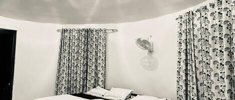 Un dormitorio con una cama grande, dos mesitas de noche, una lámpara de pared y un ventilador de techo.