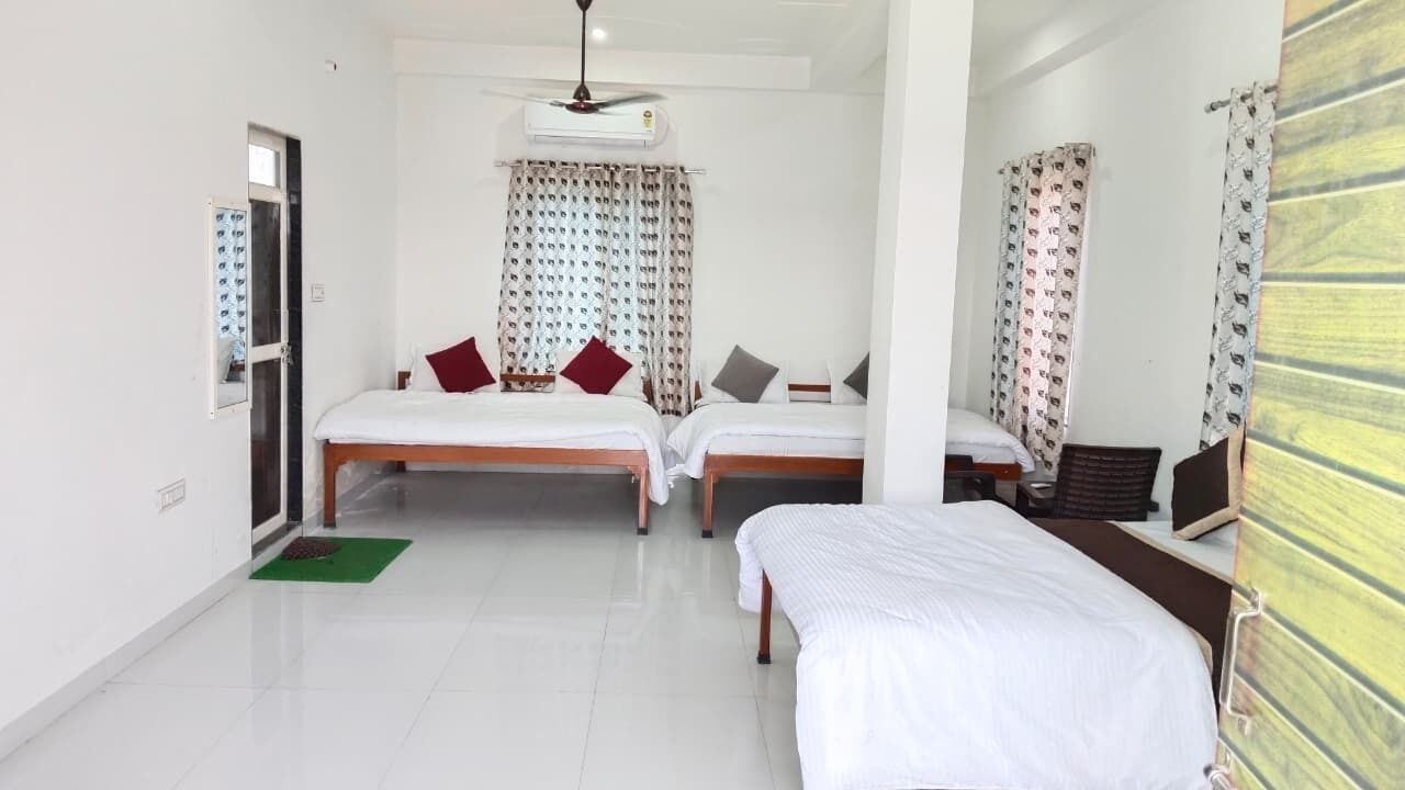 Une chambre d’hôtel avec deux lits, un bureau, une chaise, un ventilateur de plafond et une fenêtre avec des rideaux.