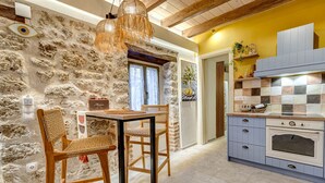 Une cuisine aux murs en pierre, avec des meubles en bois et un pare-feu en carreaux.