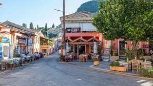Une rue avec des terrasses, un restaurant et une montagne en arrière-plan.