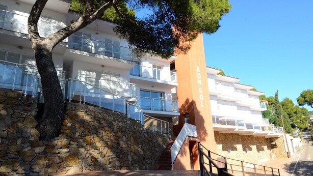 A multi-story building with balconies, a stone retaining wall, and a staircase leading to the upper floors. - Apartment in Spain near Sandy Beach (Estartit)