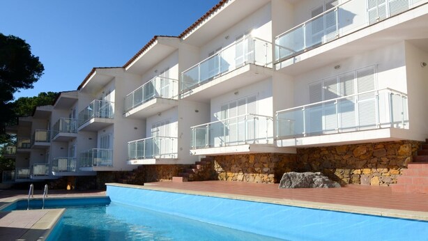 Un hôtel moderne doté d’une piscine, d’une façade en pierre et de nombreux balcons.