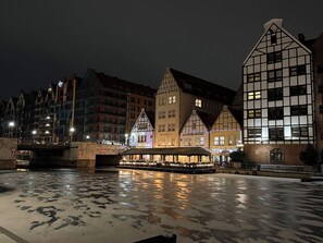 Vista de un río con un casco histórico, edificios tradicionales, un embarcadero techado y un puente.