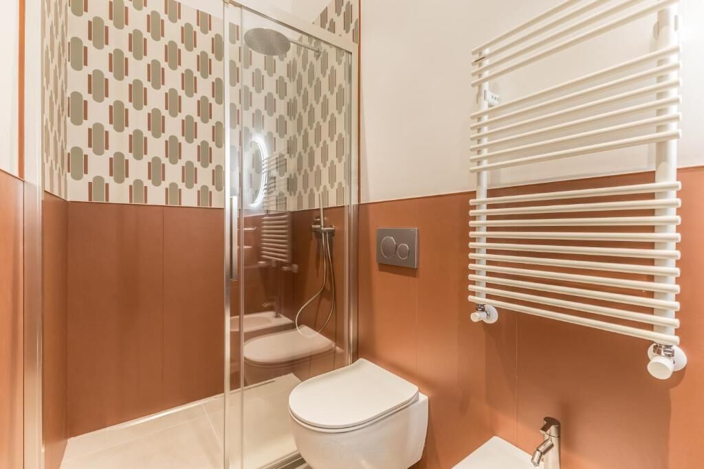 A modern bathroom with a glass shower enclosure, a toilet, and a towel rack.