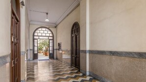Un corridoio con pavimento decorato, un'ampia porta ad arco e una pianta in vaso.