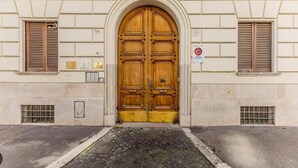 Un edificio con un'ampia porta in legno, un segnale di divieto di sosta e una piccola finestra con persiane.