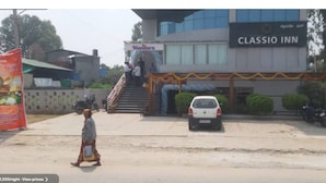 A hotel named 'CLASSIO INN' with a staircase leading to the entrance, a parked car, and a pedestrian walking on the sidewalk. - Classio Inn Hotel (Bengaluru)