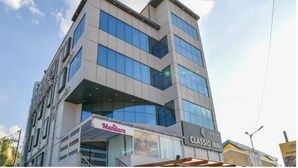 A multi-story building with a glass facade and signage for 'Mandara' and 'CLASSIO JIN'. - Classio Inn Hotel (Bengaluru)