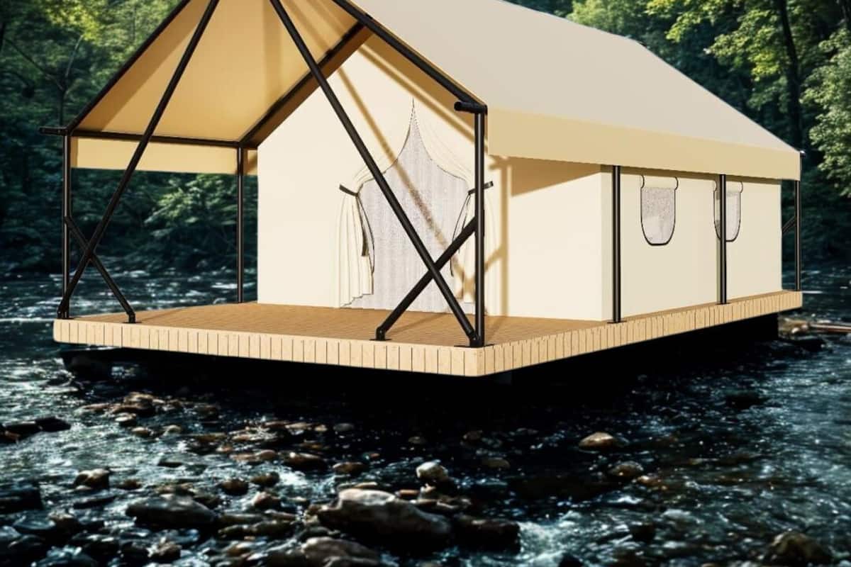 A floating house with a triangular roof, wooden deck, and a river backdrop.