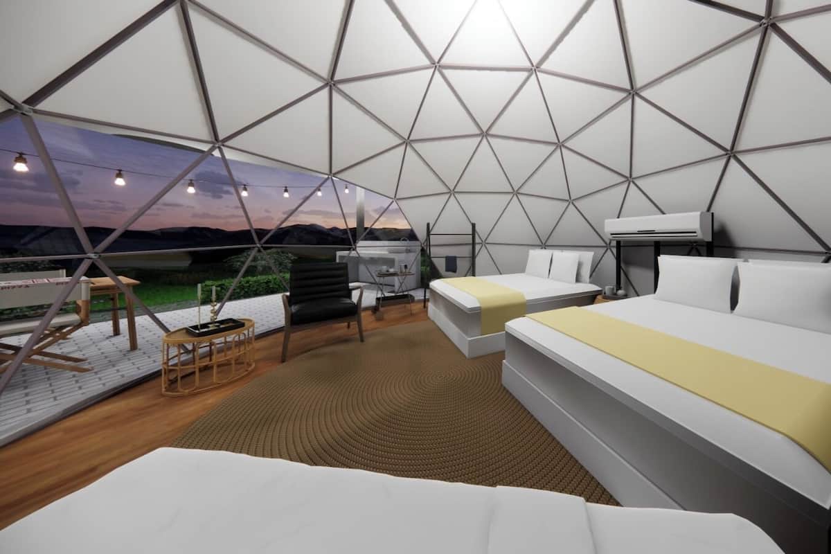 A modern, geometric-themed interior with two beds, a small seating area, and a view of the landscape.
