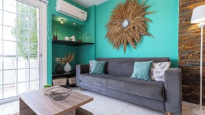 Ein modernes Wohnzimmer mit grauem Sofa, türkisfarbenen Wänden und einem dekorativen Wandbild im Sonnenstrahl-Design.