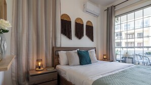 Ein Hotelzimmer mit einem großen Bett, einem Holzkopfende und Blick auf die Stadt durch ein großes Fenster.
