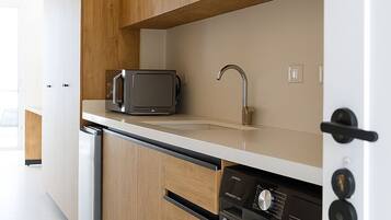 A modern kitchen with wooden cabinets, a microwave, a sink, and a washing machine.