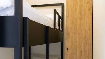 Une chambre avec des lits superposés, une armoire en bois et un climatiseur fixé au mur.