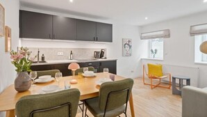 Een moderne keuken met donkere kastjes, een eettafel gedekt voor vier personen en een gele stoel.