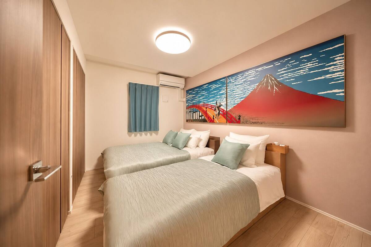 Une chambre d’hôtel avec deux lits, un tableau représentant une montagne et un rideau bleu.