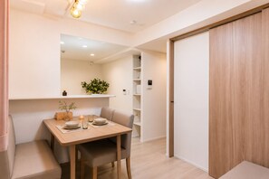 A modern dining area with a wooden table, chairs, and a built-in shelf with decorative items. - LAKU HOTEL ASAKUSA (Tokyo)