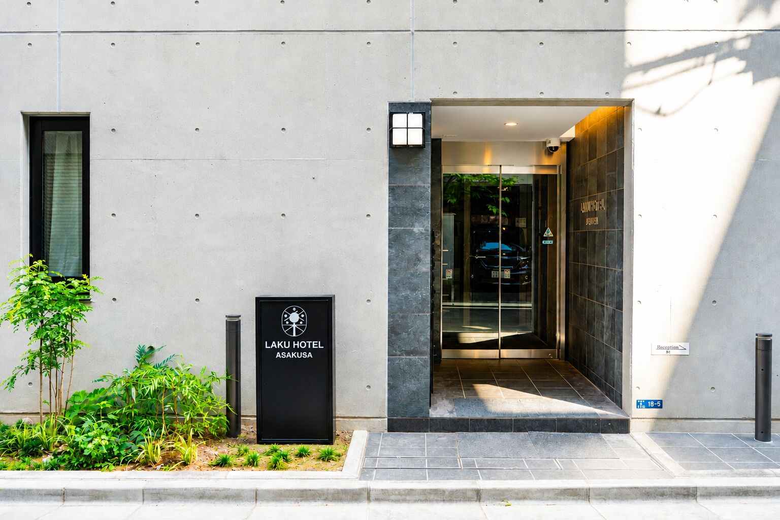 The entrance to Laku Hotel Asakusa with a reception desk and a glass door leading inside.