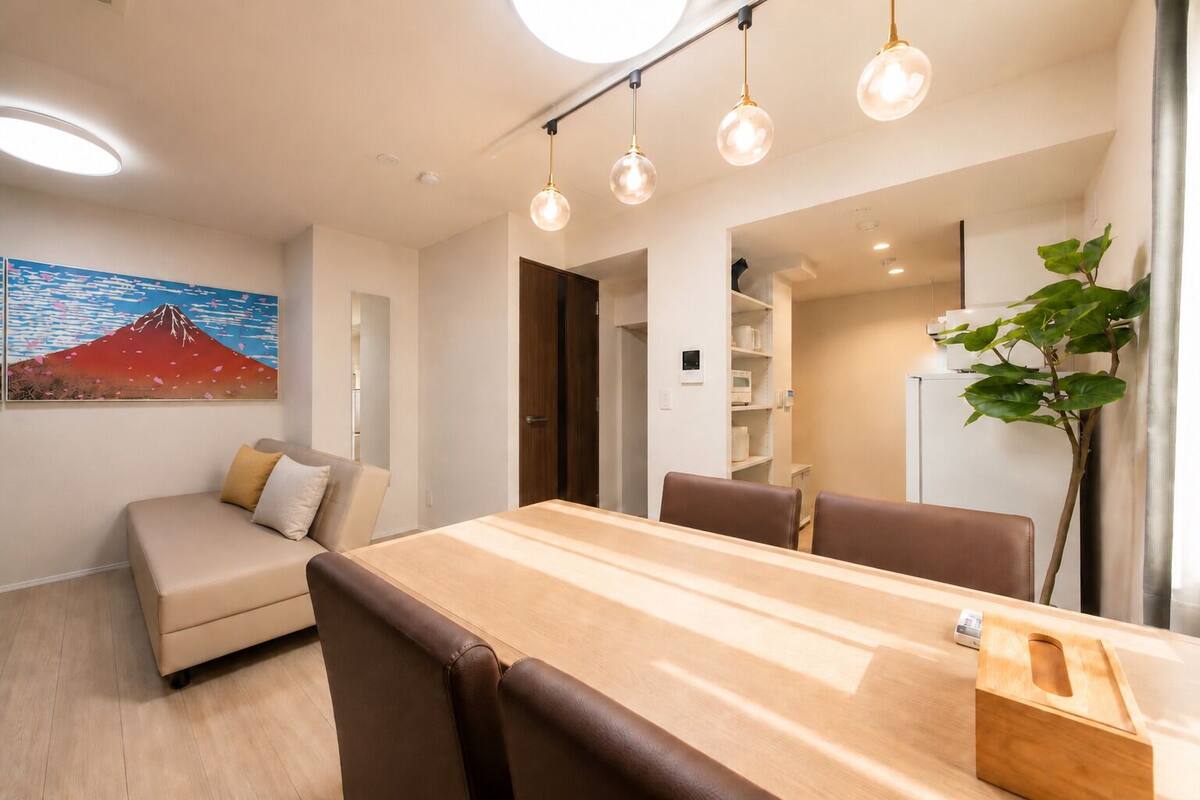 Un espace de salle à manger moderne avec une table en bois, des chaises marron, un canapé et des luminaires suspendus.
