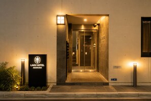 The entrance to Laku Hotel Asakusa with a reception desk, a glass door, and a signboard. - LAKU HOTEL ASAKUSA (Tokyo)