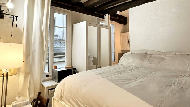 Une chambre avec un lit, un bureau avec une lampe, un four à micro-ondes et une armoire.