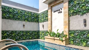 A swimming pool with a tiled floor, surrounded by walls with green foliage and a sign reading 'Deceva's Villa'. - Calma Villa Panorama, Batu Malang (Batu)