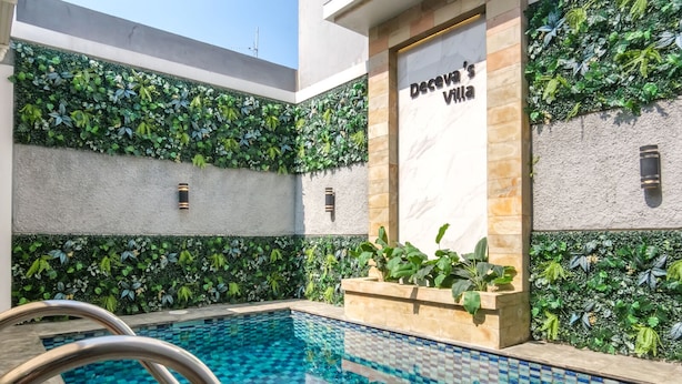 Ein Swimmingpool mit Kachelboden, umgeben von Mauern mit Grünpflanzen und einem Schild mit der Aufschrift 'Deceva's Villa'.
