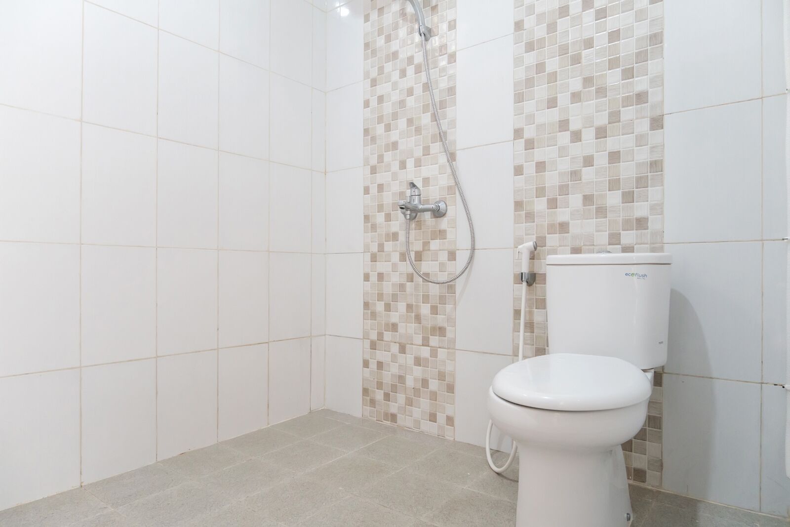 Une salle de bain avec douche, toilettes et murs carrelés.