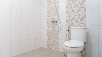 Une salle de bain avec douche, toilettes et murs carrelés.