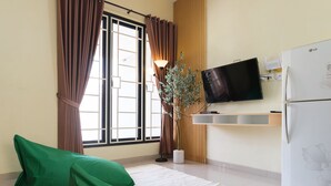 Eine moderne Küche mit Flachbildfernseher, einem weißen Kühlschrank und einem Fenster mit Vorhängen.