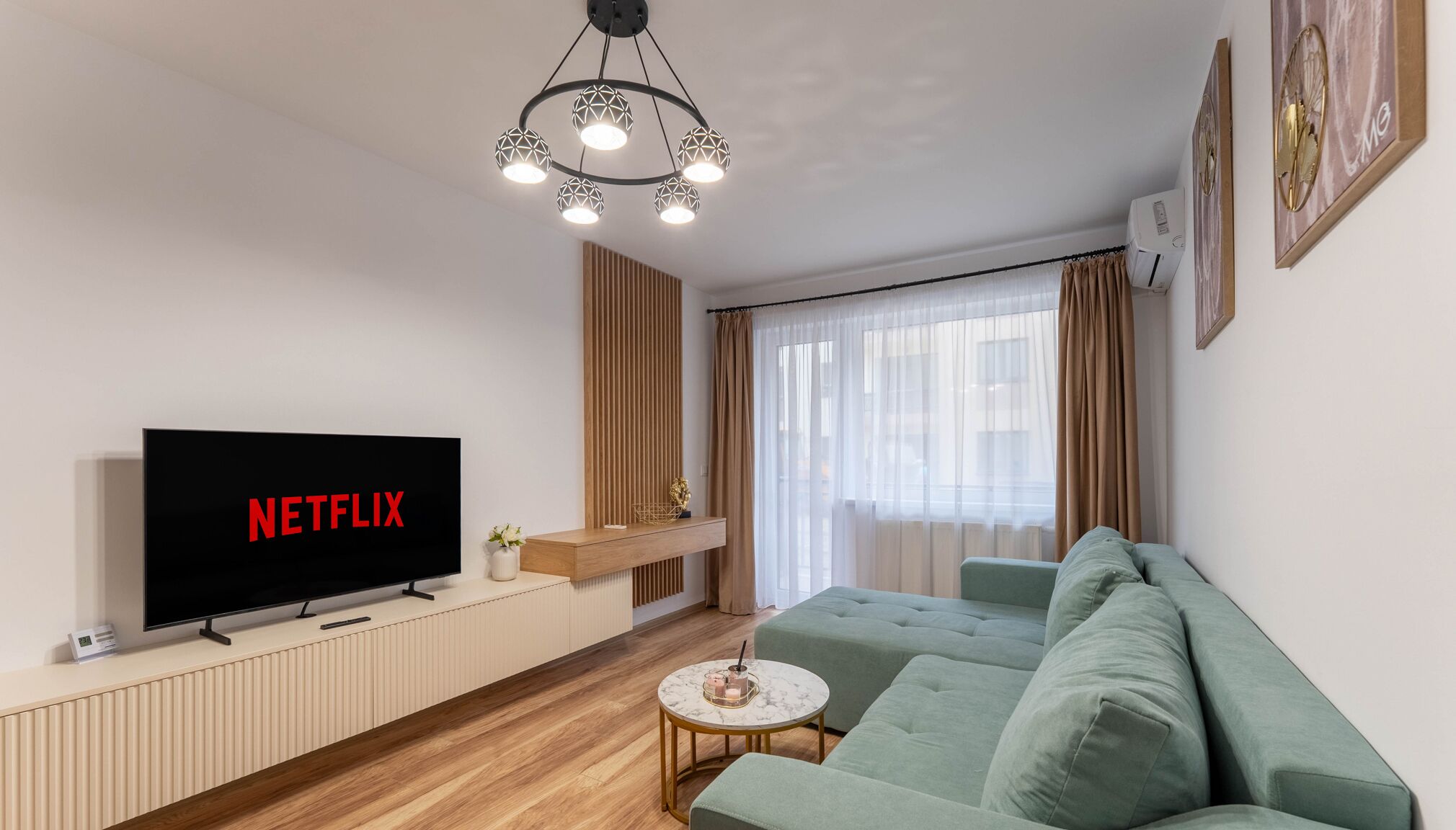 Una sala de estar moderna con un televisor de pantalla plana, una mesa de centro redonda y un sofá verde.