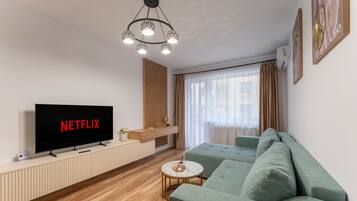 Una sala de estar moderna con un televisor de pantalla plana, una mesa de centro redonda y un sofá verde.